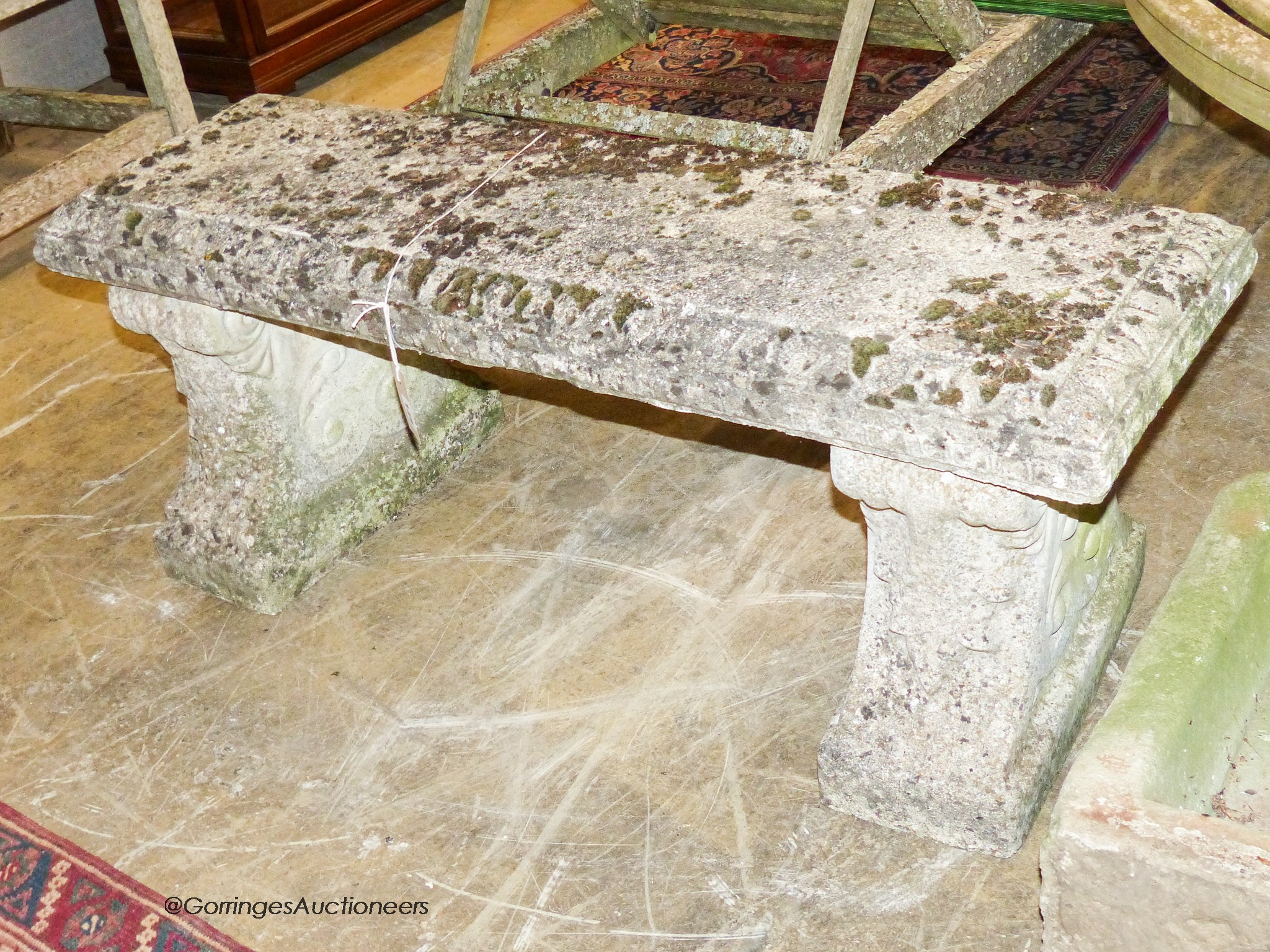 A reconstituted stone bench having moulded rectangular top on acanthus-decorated end supports, width 112cm, depth 36cm, height 42cm